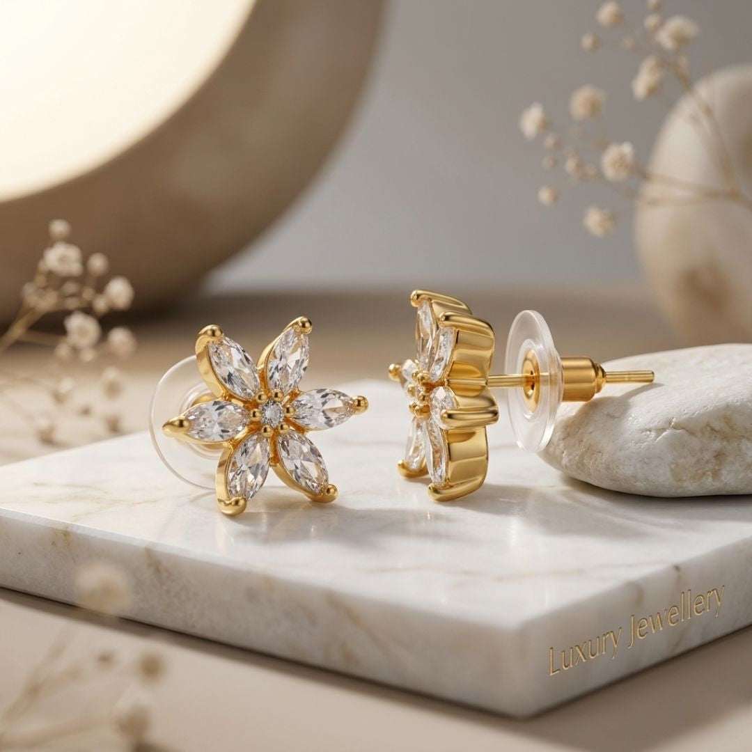 Gold floral earrings on a marble surface with 'Luxury Jewellers' branding.