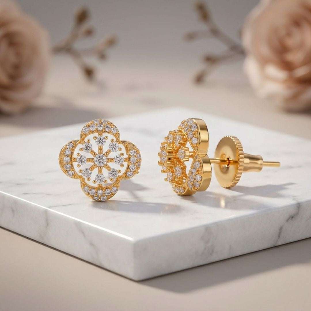 Gold earrings with floral design on a marble surface with flowers in the background