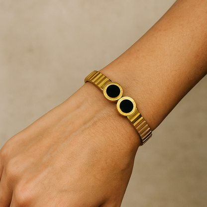 Gold Bracelet for Women with black circular accents on a wrist against a beige background