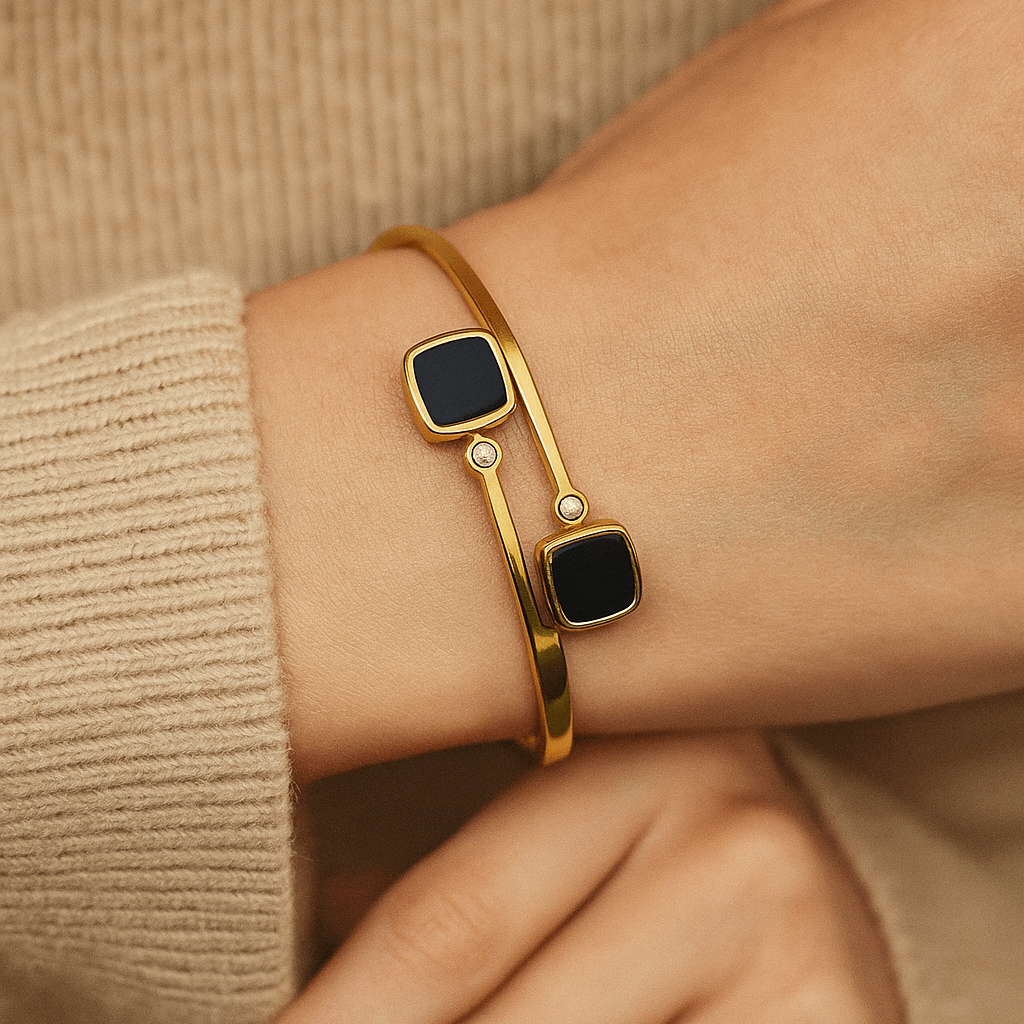 Gold Bracelet for Women with black square stones on a wrist against a beige background