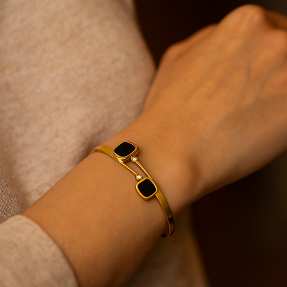 Gold Bracelet for Women with black stones on a wrist against a neutral background
