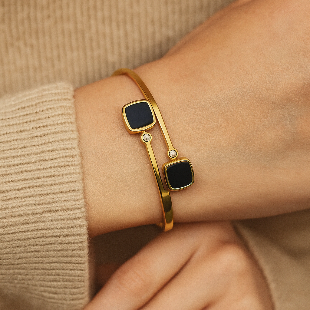 Gold Bracelet for Women with black square stones on a wrist against a beige background