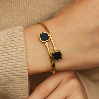 Gold Bracelet for Women with black square stones on a wrist against a beige background