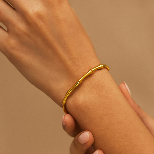 Gold Bracelet for Women on a wrist against a beige background