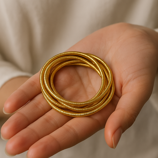 Hand holding multiple gold Bracelet for Women against a neutral background