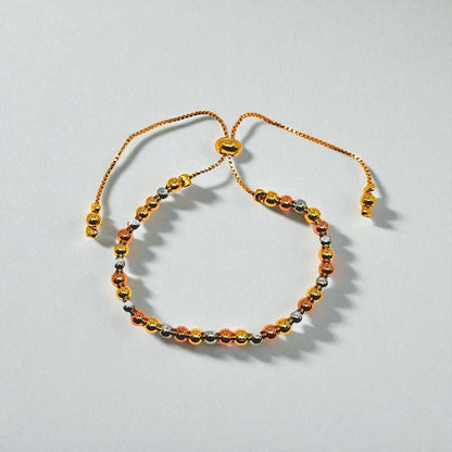 Gold beaded bracelet for Women held in a hand against a beige background