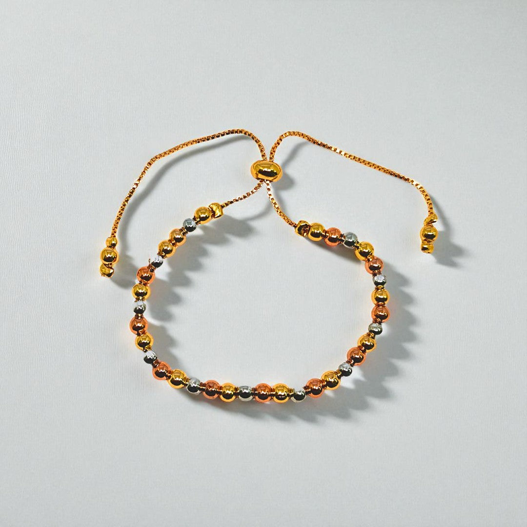 Gold beaded bracelet for Women held in a hand against a beige background