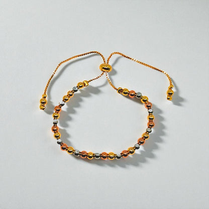Gold beaded bracelet for Women held in a hand against a beige background
