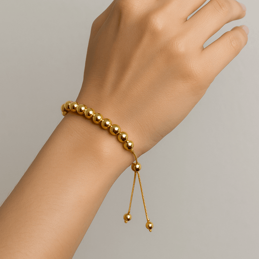 Gold beaded Bracelet for Women on a wrist against a neutral background
