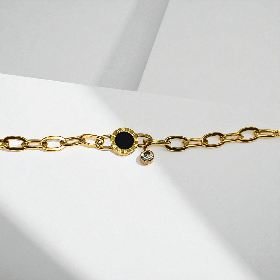 Gold chain Bracelet for Women with a black gemstone and small clear gemstone on a light gray background