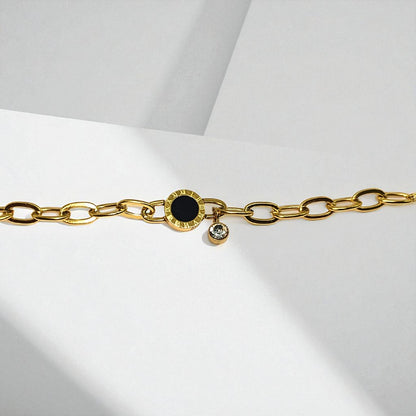 Gold chain Bracelet for Women with a black gemstone and small clear gemstone on a light gray background