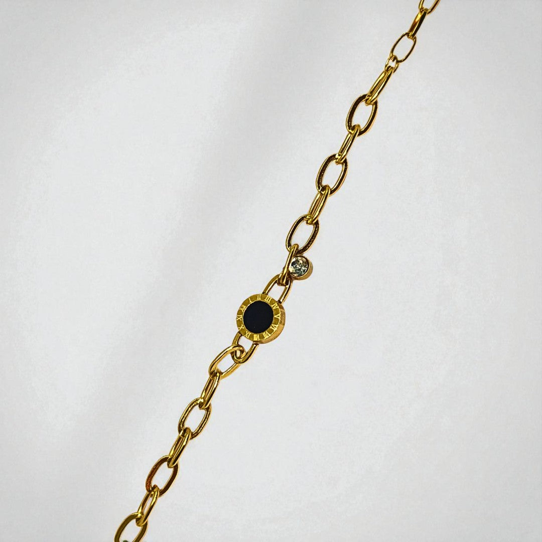 Gold chain Bracelet for Women with black and green gemstones on a light gray background