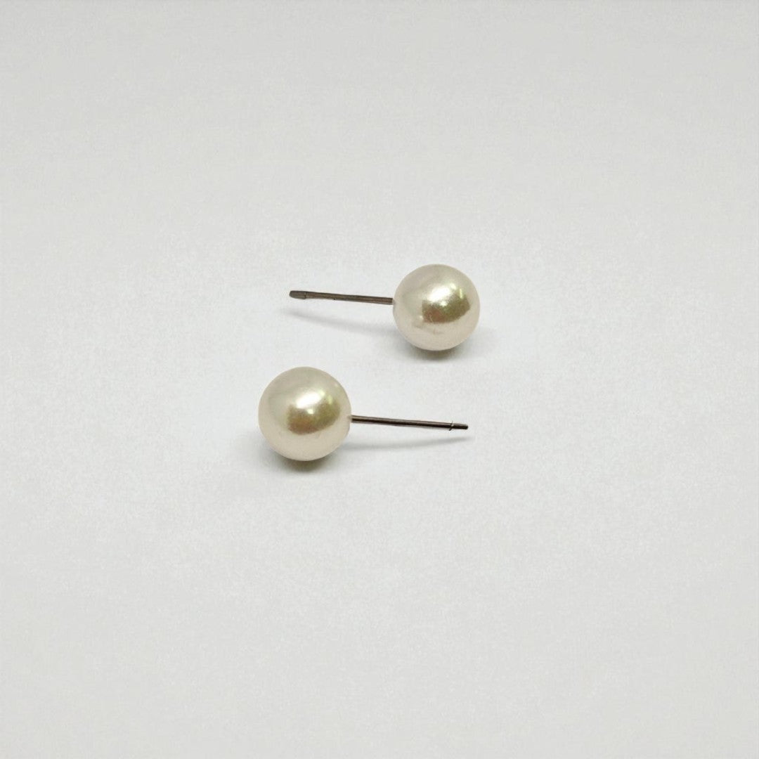 Pair of pearl stud earrings for women on a light gray background