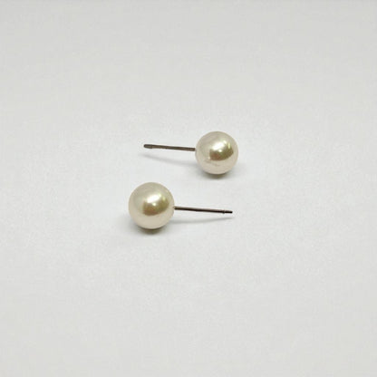 Pair of pearl stud earrings for women on a light gray background