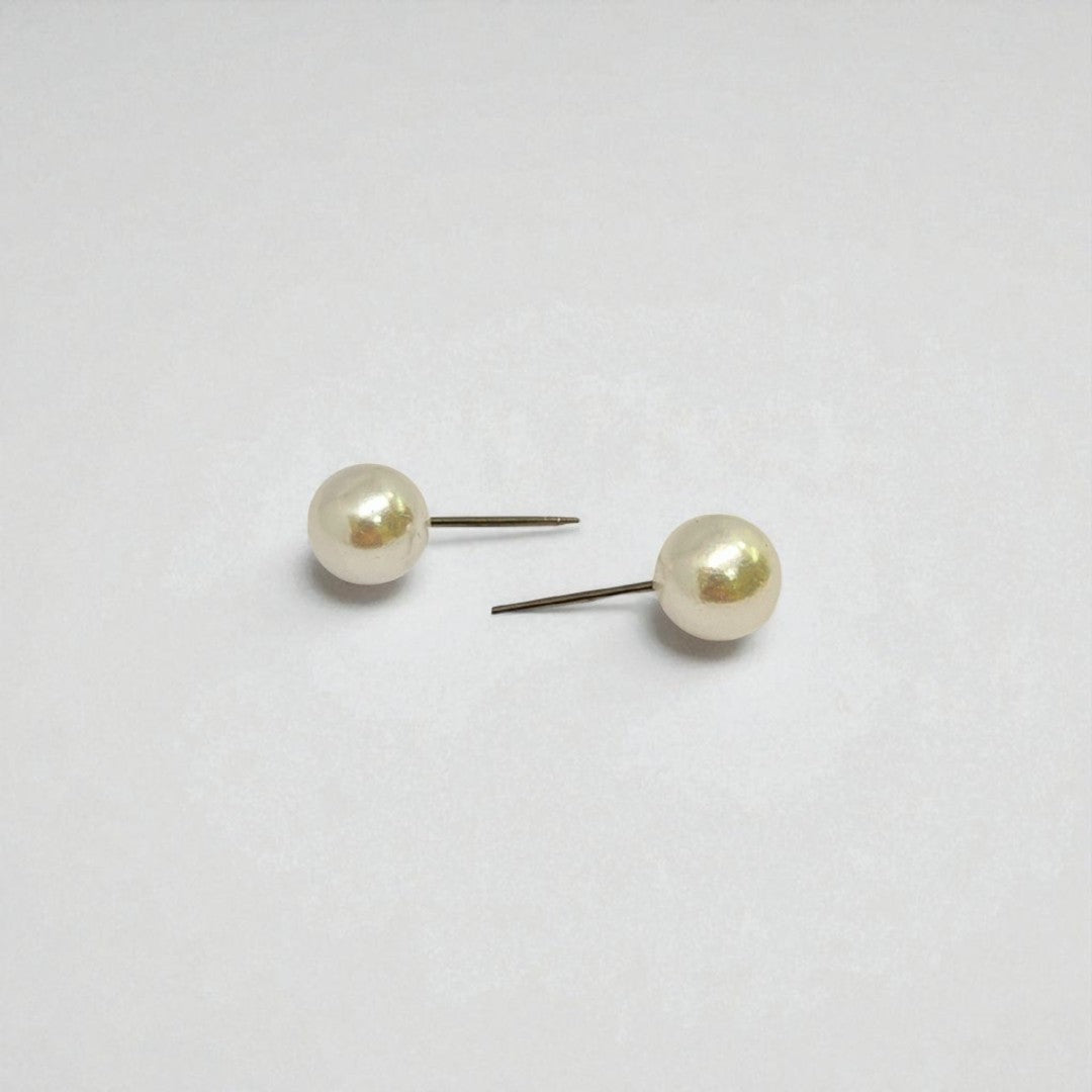 Pair of pearl stud earrings for women on a light gray background