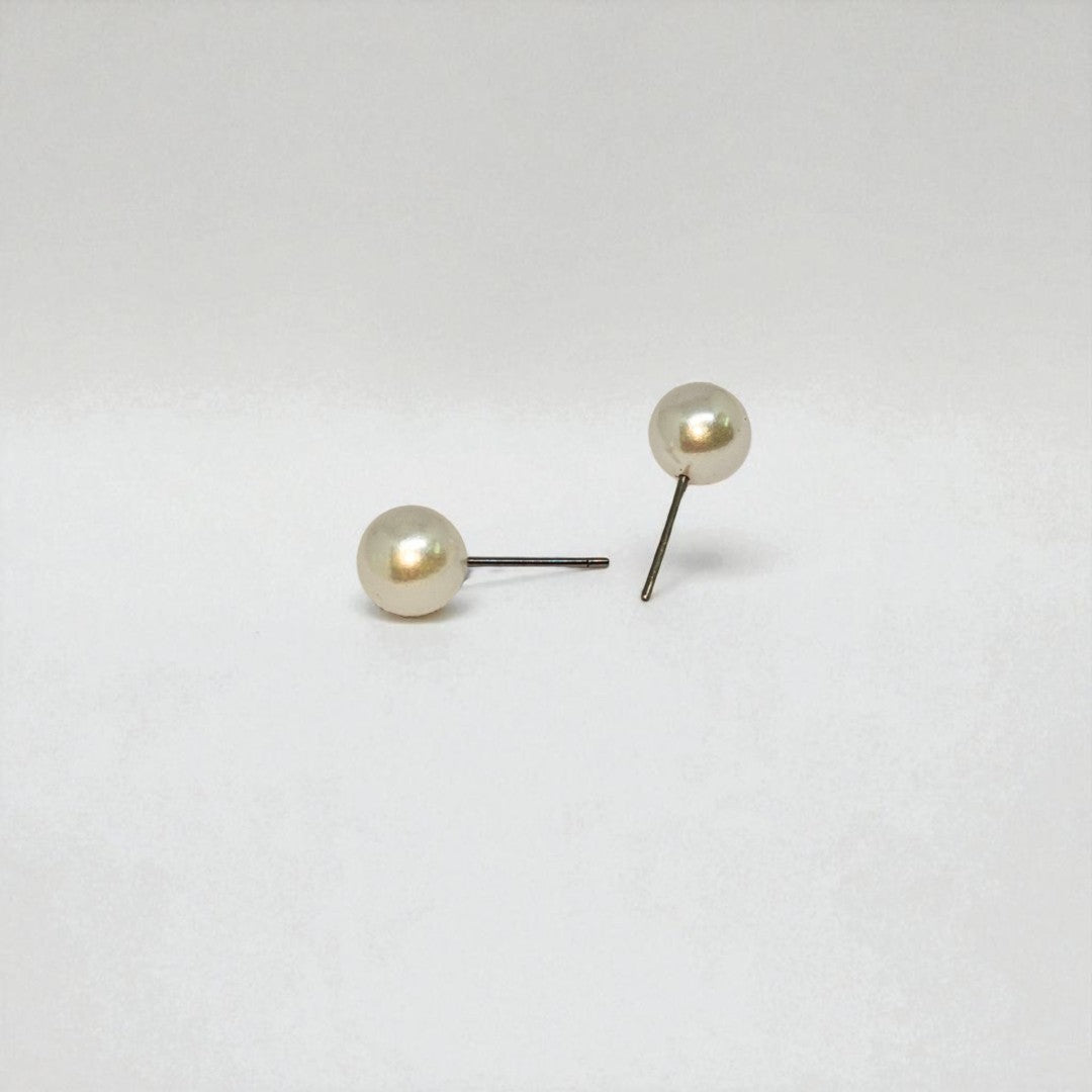 Pair of pearl stud earrings for women on a light gray background