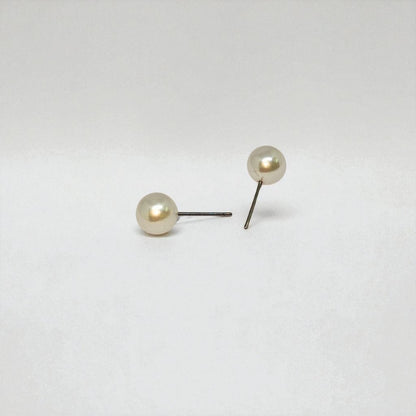 Pair of pearl stud earrings for women on a light gray background