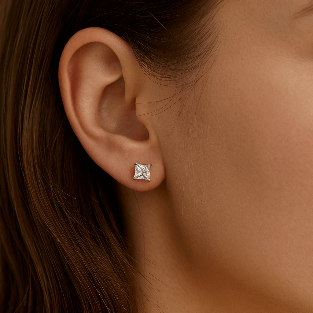 Close-up of an ear wearing a diamond earring with a neutral background
