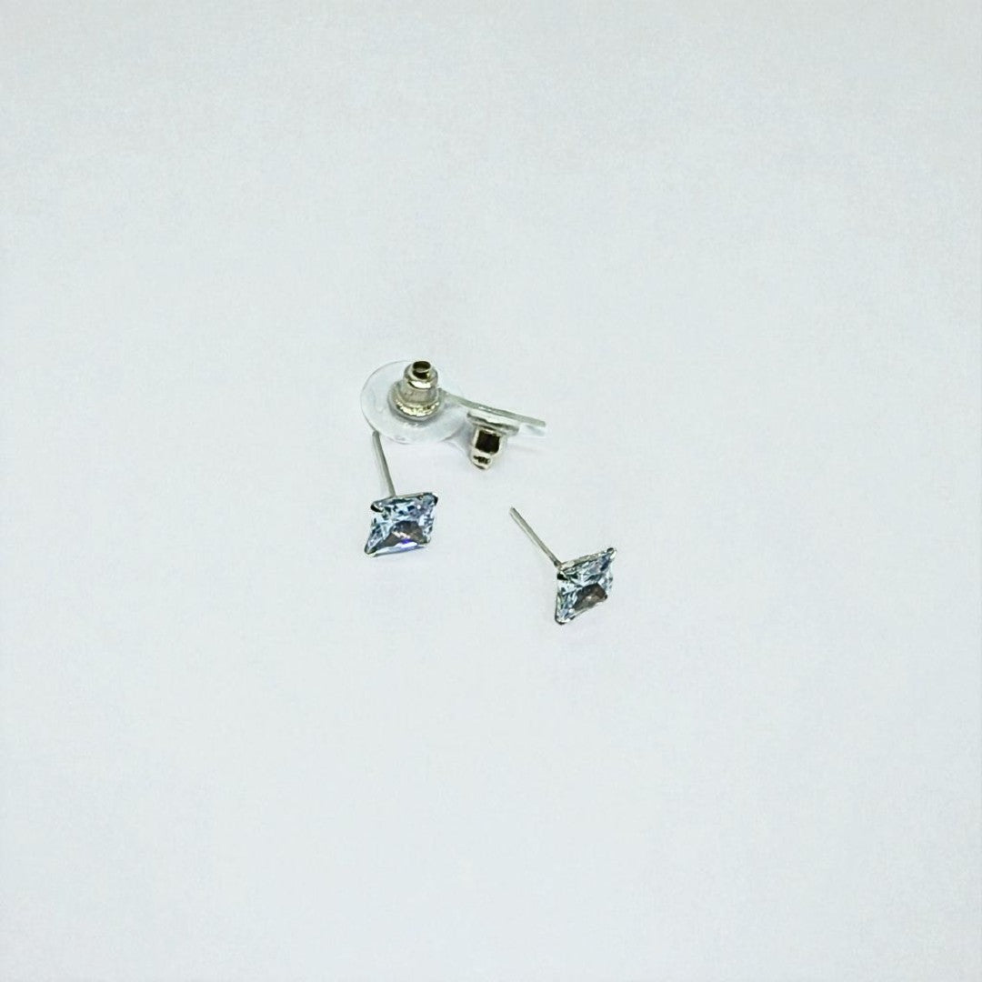 Pair of silver earrings for women with clear gemstones on a light gray background