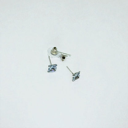 Pair of silver earrings for women with clear gemstones on a light gray background