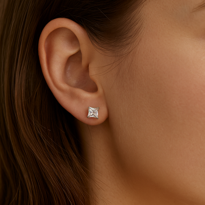 Close-up of an ear wearing a diamond earring with a neutral background