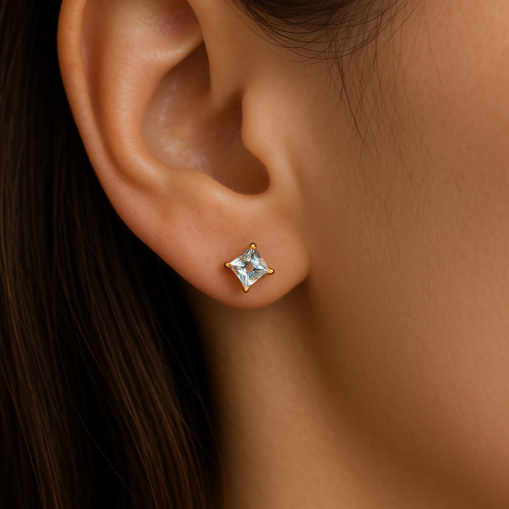 Close-up of an ear wearing a diamond stud earring with dark hair and skin background