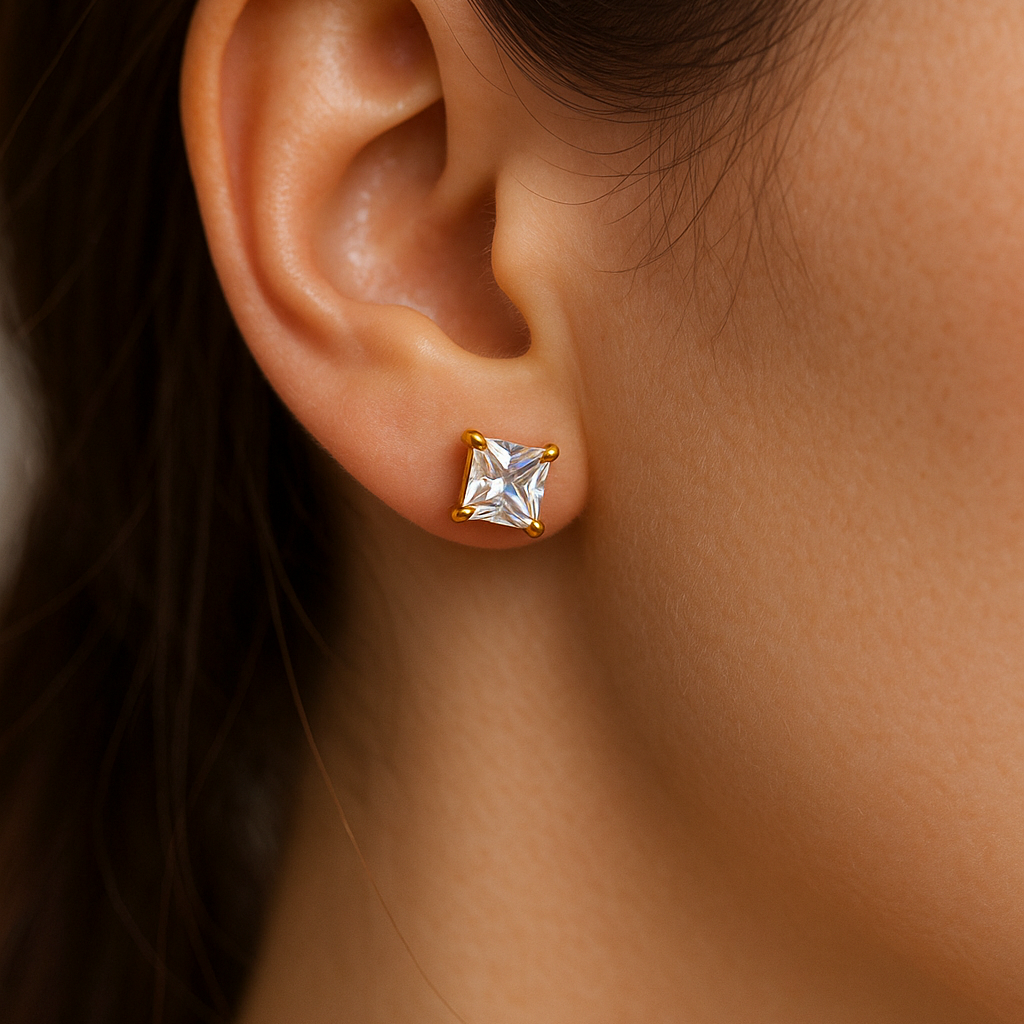 Gold earring for women with a clear gemstone worn by a person