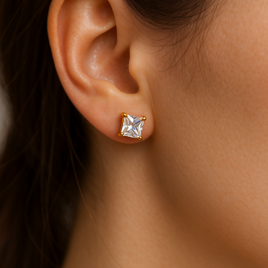 Gold earring for women with a clear gemstone worn by a person