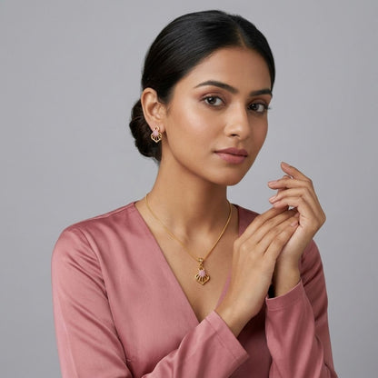 Woman wearing gold pendant necklace and matching stud earrings with pink stones