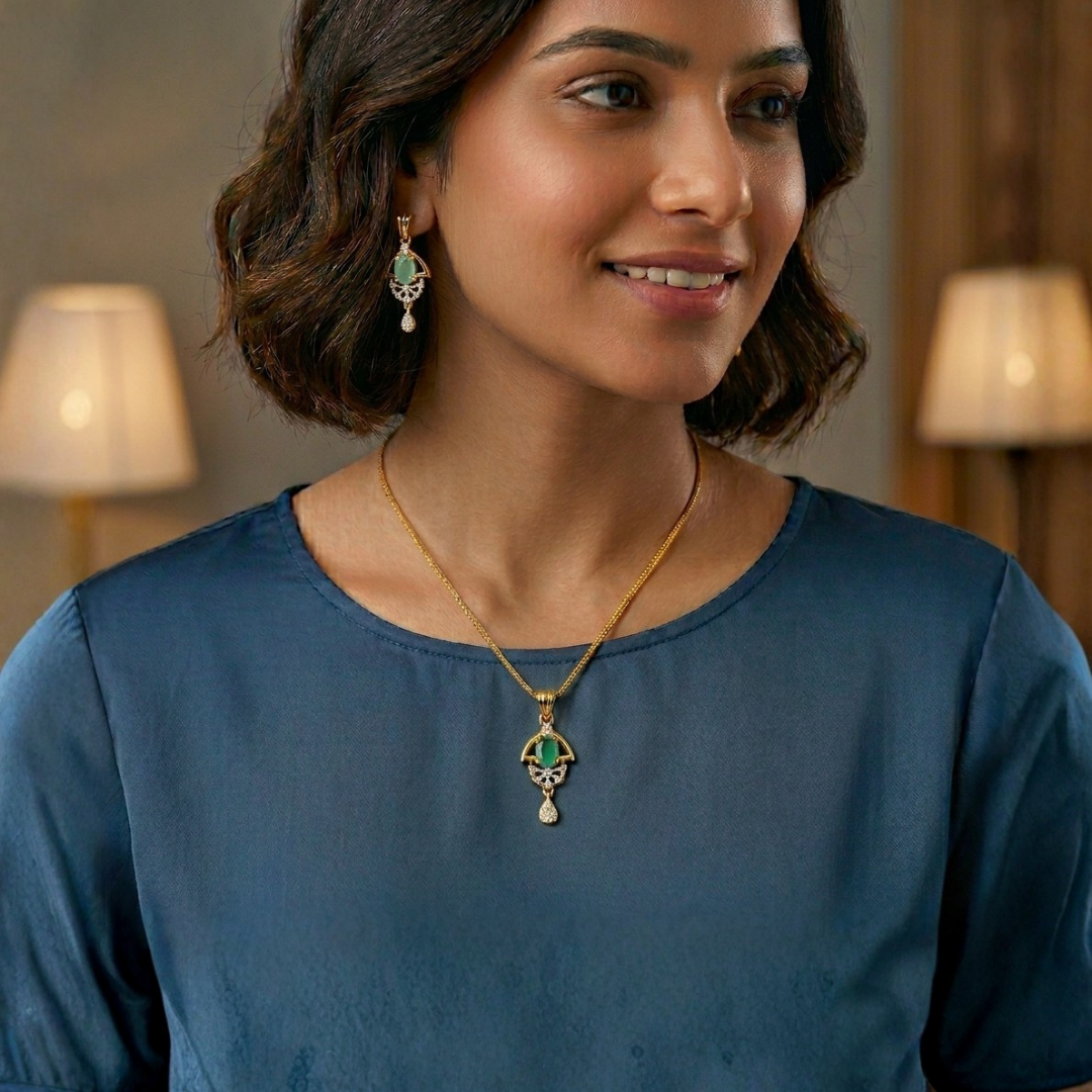 Woman wearing a gold necklace with an emerald pendant and matching earrings indoors.