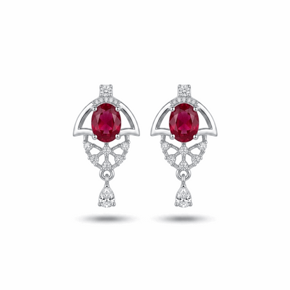Pair of earrings with red gemstones and diamond accents on a white background