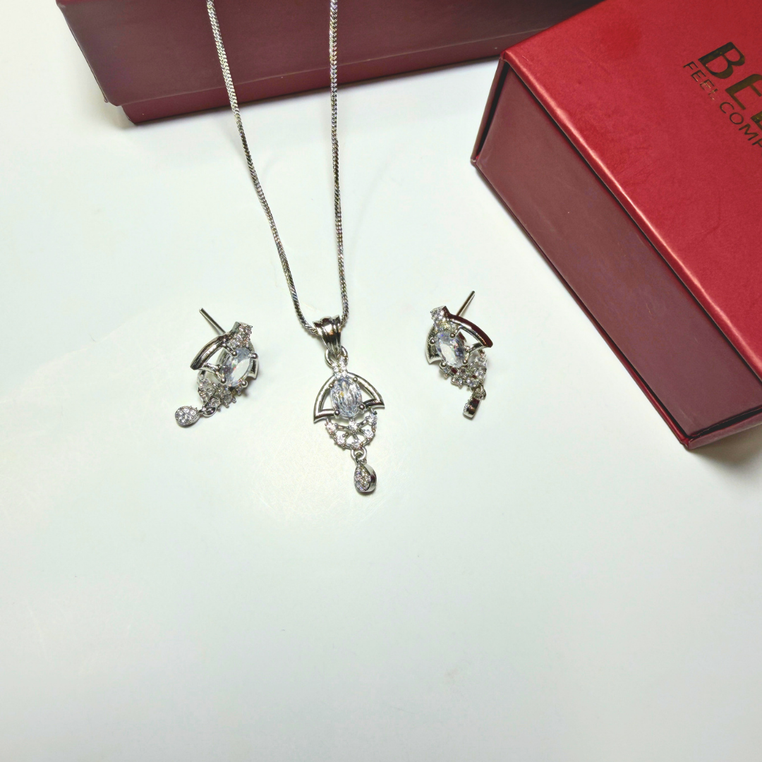 Jewelry set with necklace and earrings on a white surface next to a red box.