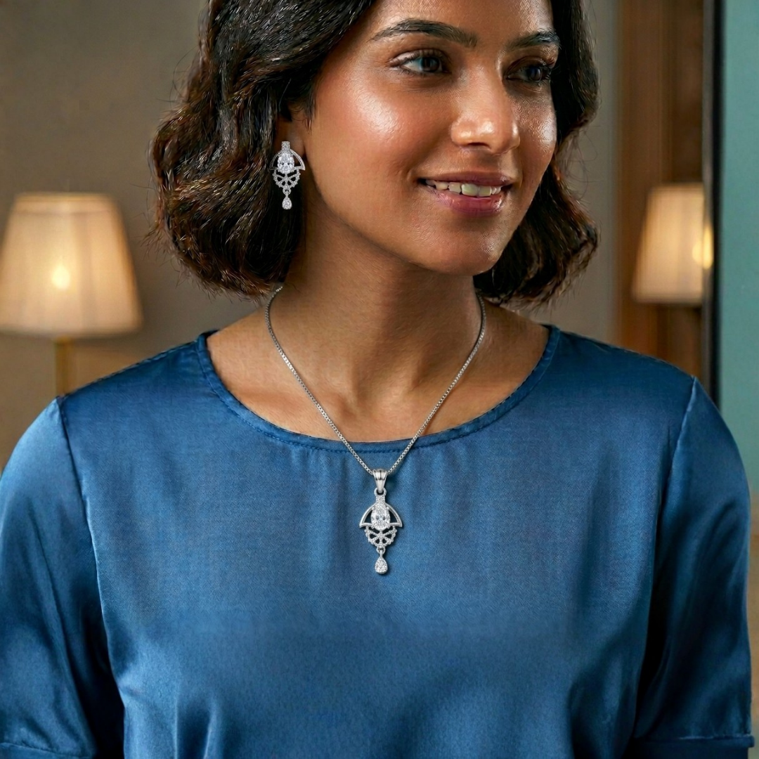 Woman wearing a silver necklace and earrings in a softly lit room.