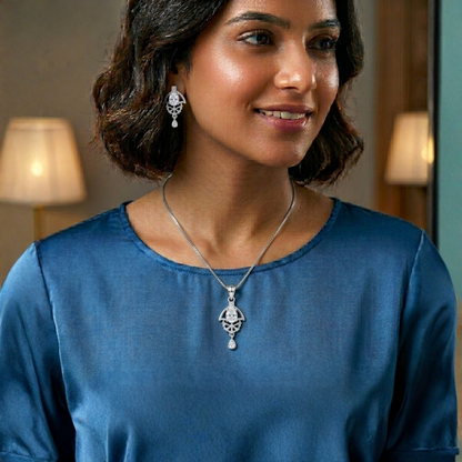 Woman wearing a silver necklace and earrings in a softly lit room.