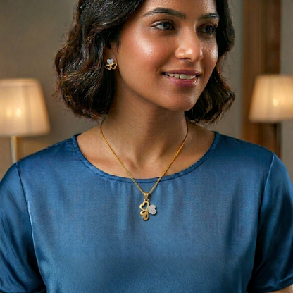 Woman wearing a gold necklace with a clover pendant in a softly lit room.