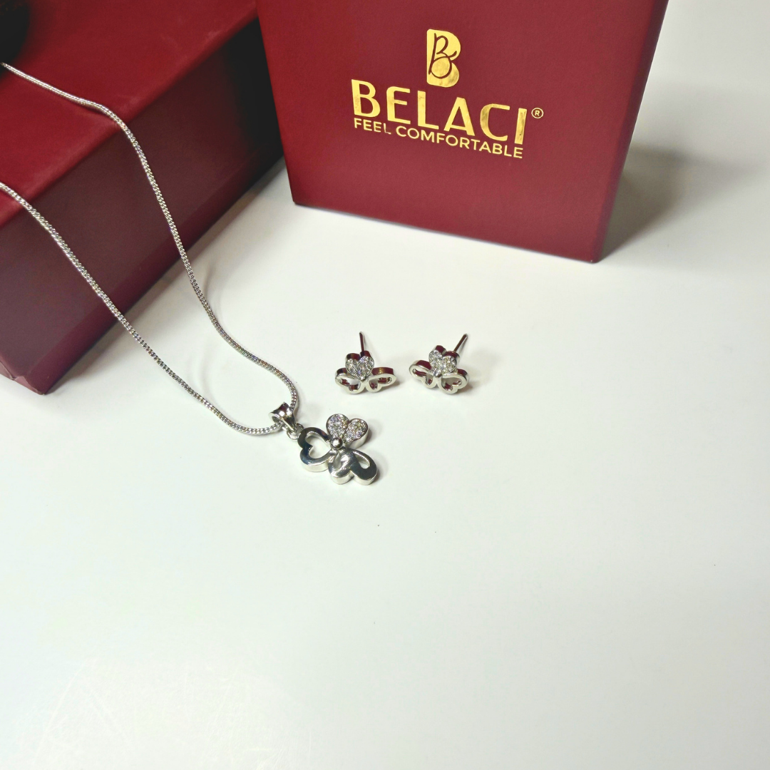 Silver jewelry set with necklace and earrings on a white surface, Belaci box in the background.