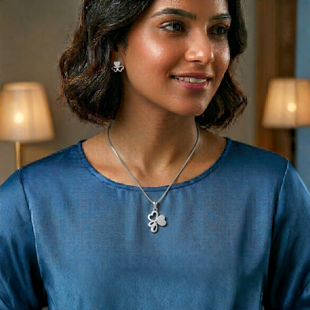 Woman wearing a gold necklace with a clover pendant in a softly lit room.