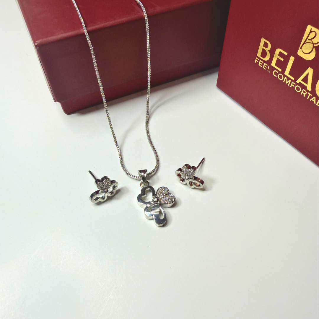 Silver jewelry set with necklace and earrings on a white surface, Beladora brand visible.