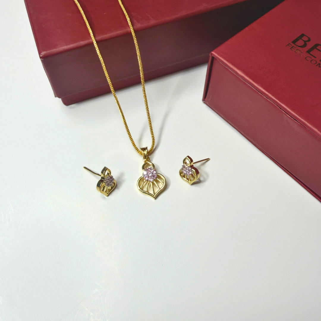 Gold jewelry set with necklace and earrings on a white surface with a red box in the background.