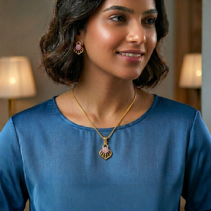 Woman wearing a blue top and gold necklace with a pendant indoors.