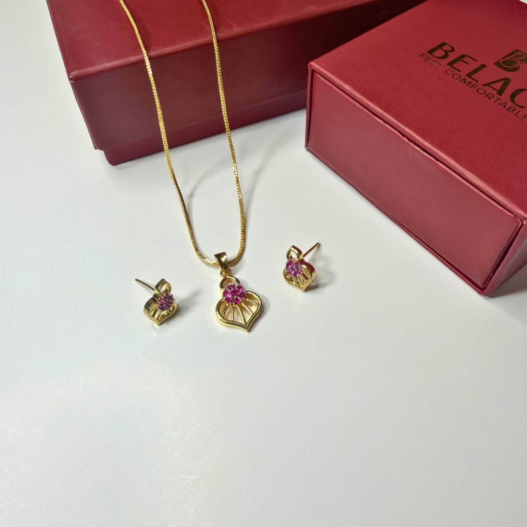 Gold jewelry set with pink stones on a white surface next to a Beladora box.