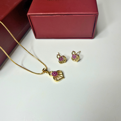 Gold necklace and earrings with pink gemstones on a white surface next to a red jewelry box.