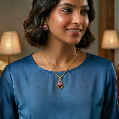 Woman wearing a blue top and gold necklace with a pendant indoors.