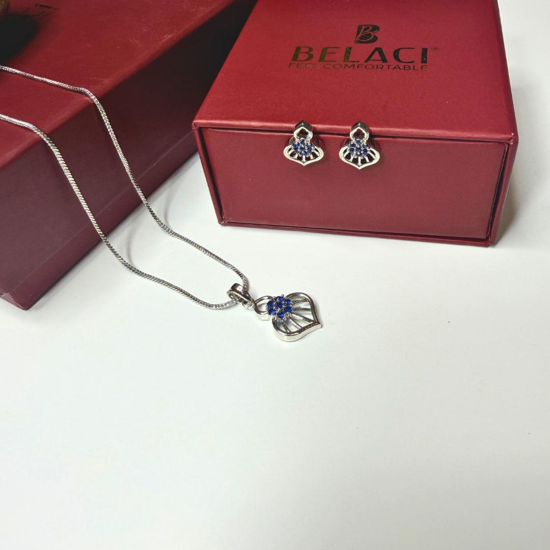 Silver necklace and earrings with blue stones on a white surface, next to a red BELACCI box.