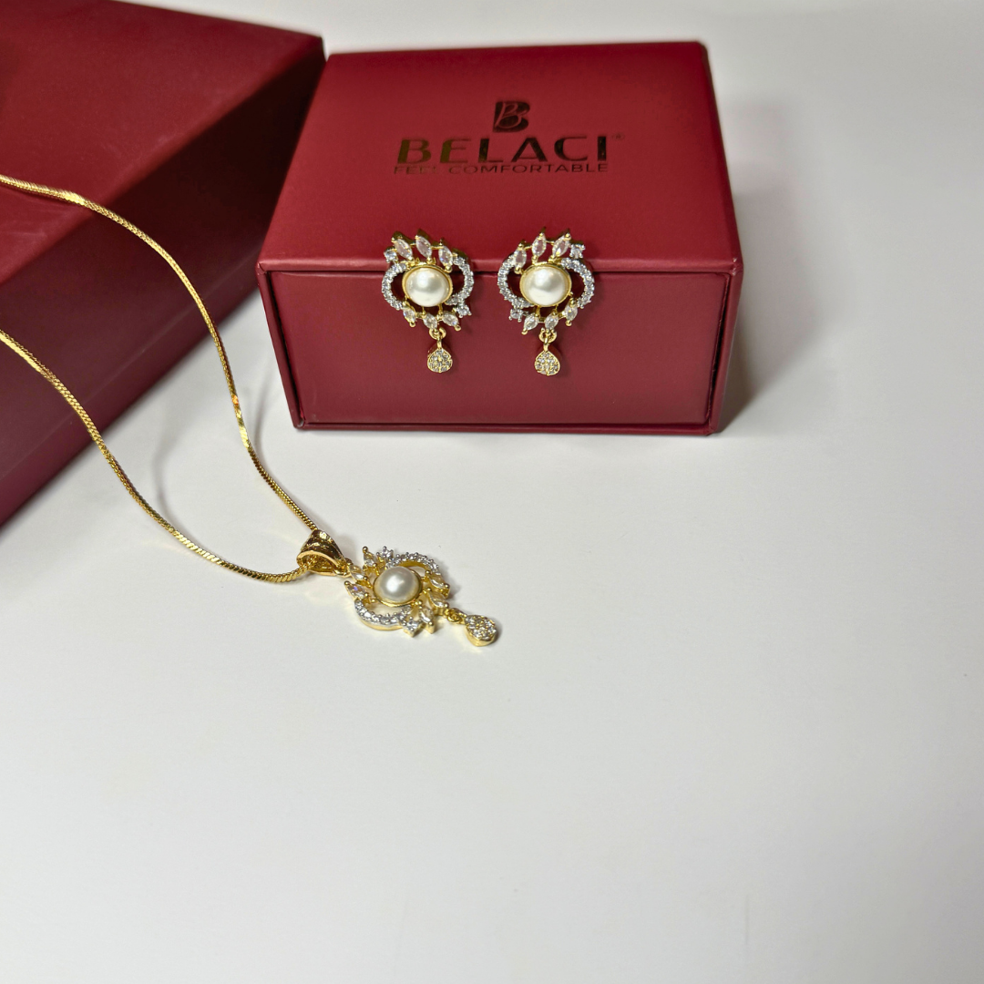Gold necklace and earrings with pearl accents in front of a Belaci box on a white background