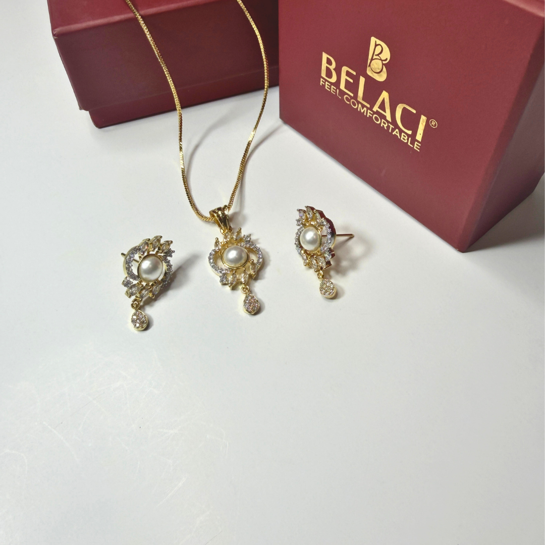 Gold jewelry set with pearl accents on a white surface, featuring a BELACI box in the background.