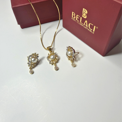 Gold jewelry set with pearl accents on a white surface, featuring a BELACI box in the background.