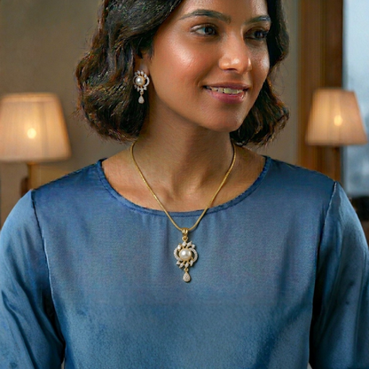 Woman wearing a gold necklace with a pendant and pearl earrings indoors.