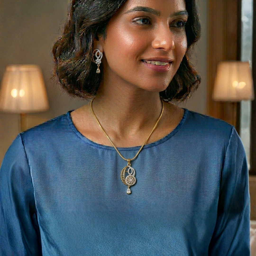 Woman wearing a blue top and gold necklace with a pendant indoors.
