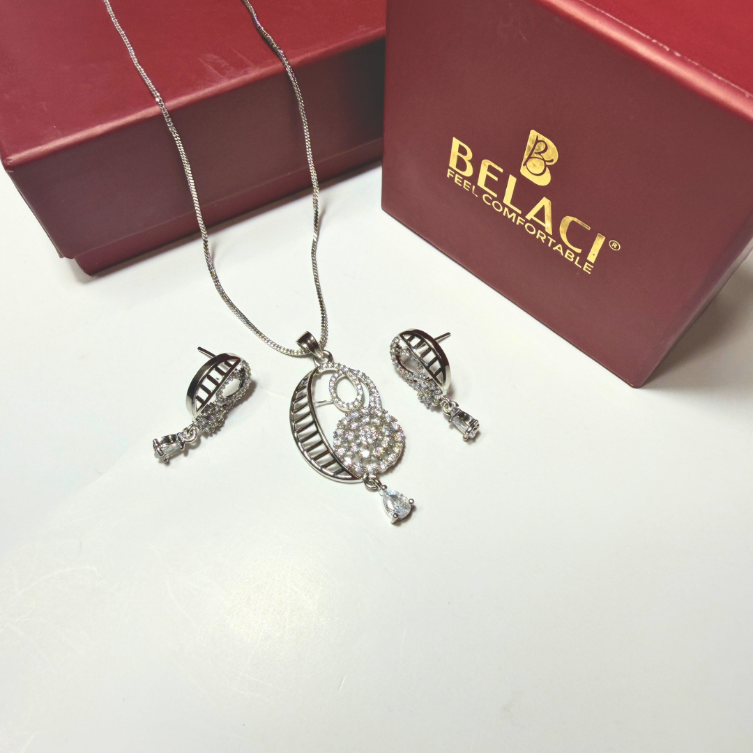 Silver jewelry set with necklace and earrings on a white surface, Belaci brand visible.